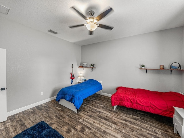 bedroom with visible vents, baseboards, a textured ceiling, and wood finished floors