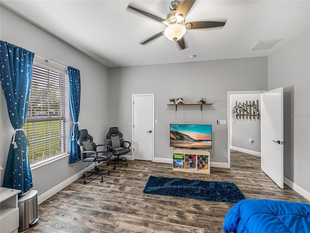 bedroom featuring a ceiling fan, wood finished floors, baseboards, and a textured ceiling
