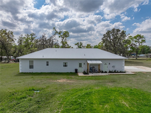 back of house with a patio area, a lawn, and metal roof