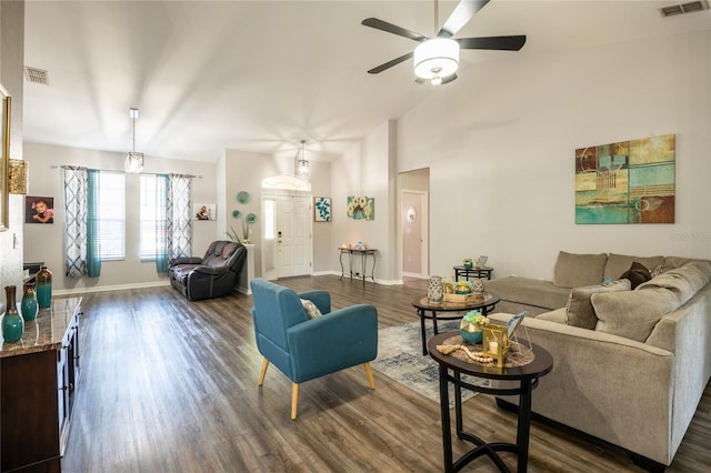 living room with ceiling fan, visible vents, baseboards, and dark wood finished floors