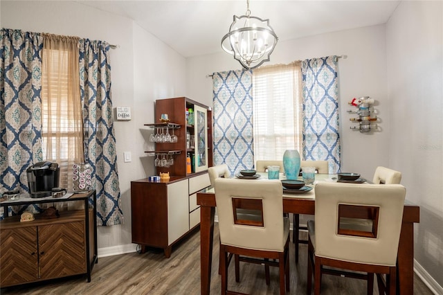 dining area with baseboards, an inviting chandelier, and wood finished floors