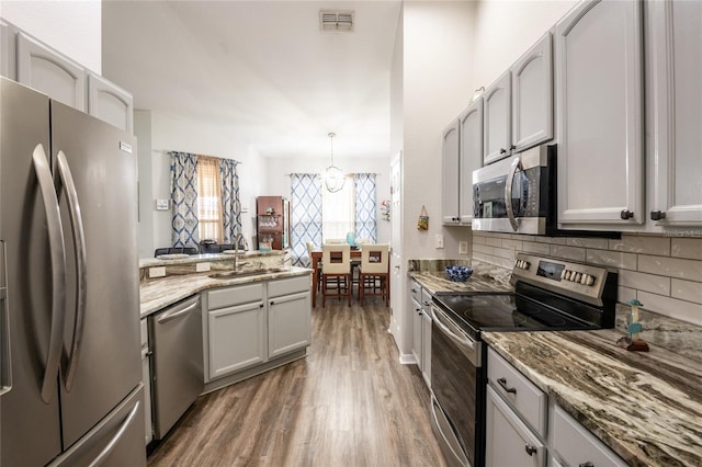 5416 Oxford Manor Cir, Lakeland, FL 33810 - kitchen with visible vents, a sink, tasteful backsplash, wood finished floors, and appliances with stainless steel finishes