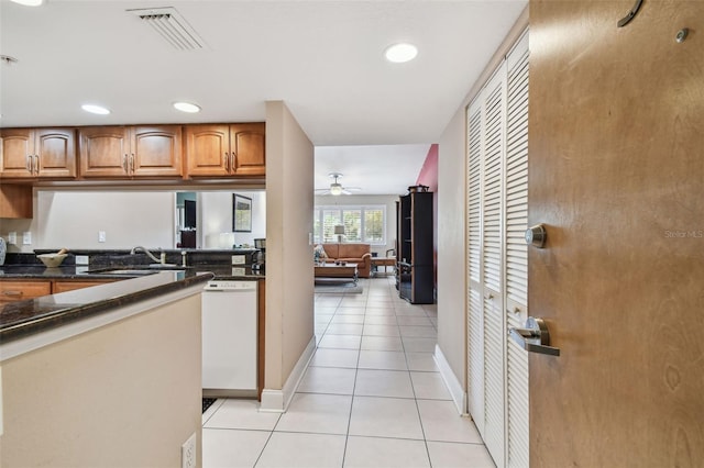 kitchen featuring visible vents, brown cabinets, a sink, light tile patterned flooring, and white dishwasher