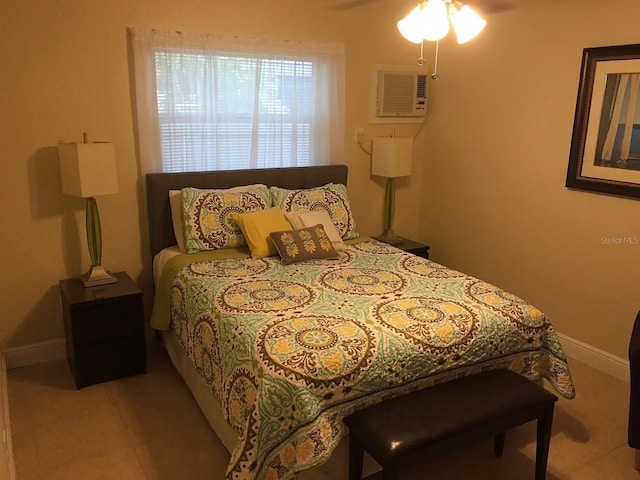 bedroom featuring an AC wall unit, baseboards, and tile patterned floors