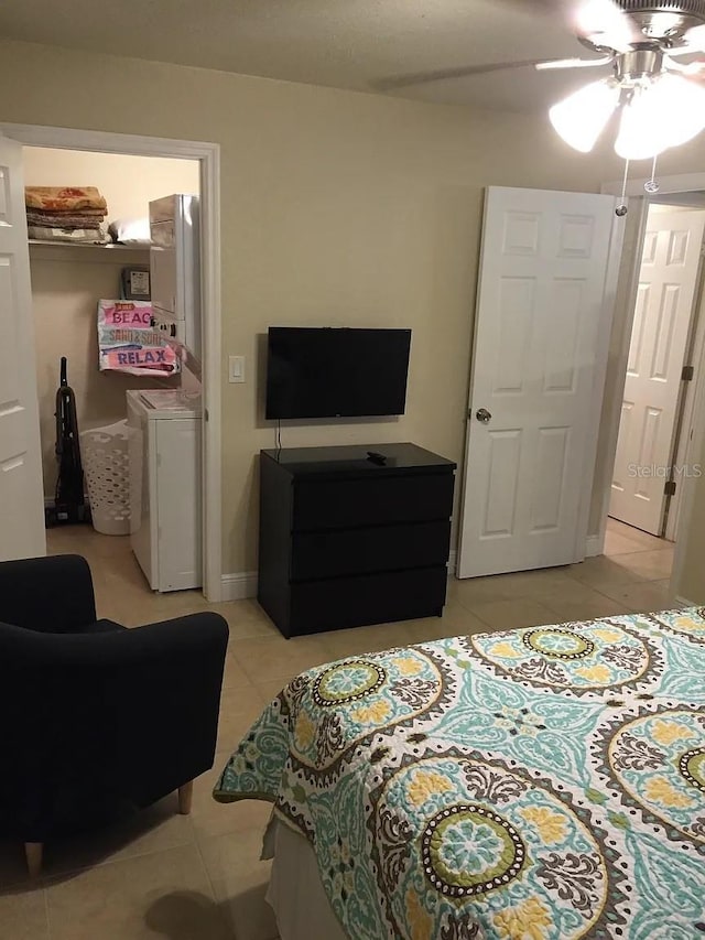 bedroom featuring light tile patterned flooring, washer / dryer, and a ceiling fan