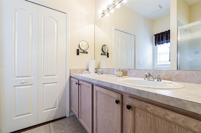 bathroom with a sink, visible vents, double vanity, and tile patterned floors