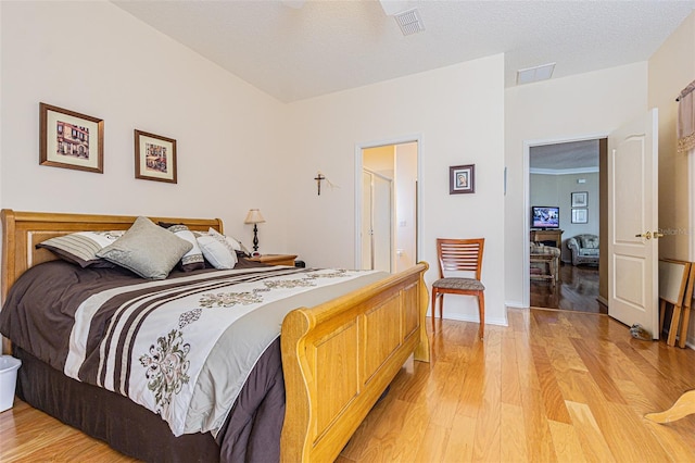 bedroom with light wood-style flooring, baseboards, visible vents, and a textured ceiling