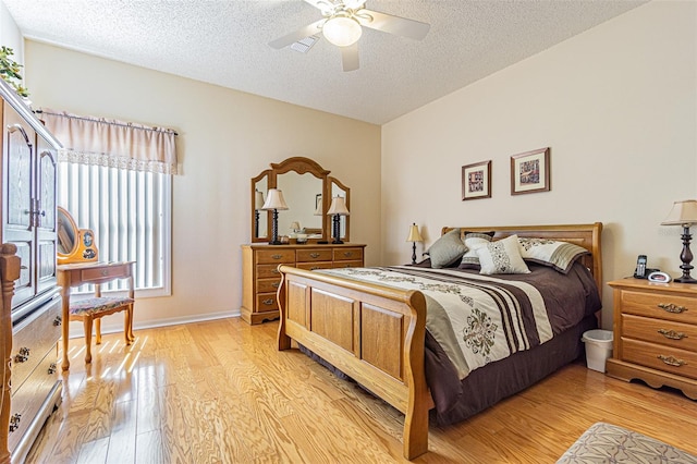 bedroom with baseboards, a textured ceiling, a ceiling fan, and light wood finished floors