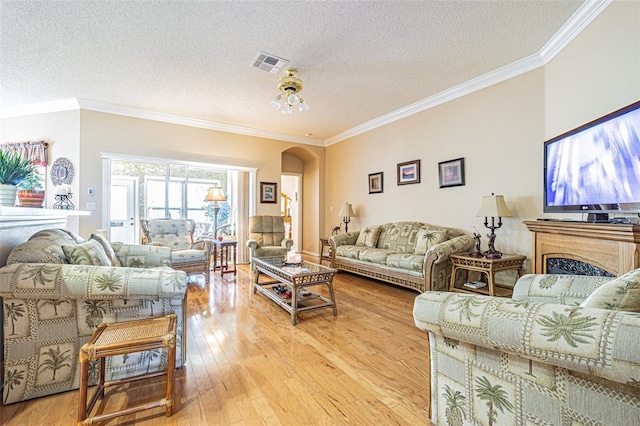 living room with arched walkways, light wood-style floors, and crown molding