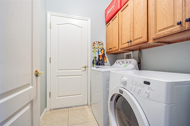 washroom featuring light tile patterned flooring, cabinet space, and washer and clothes dryer