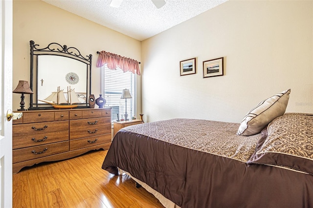 bedroom with light wood-style floors, a ceiling fan, and a textured ceiling