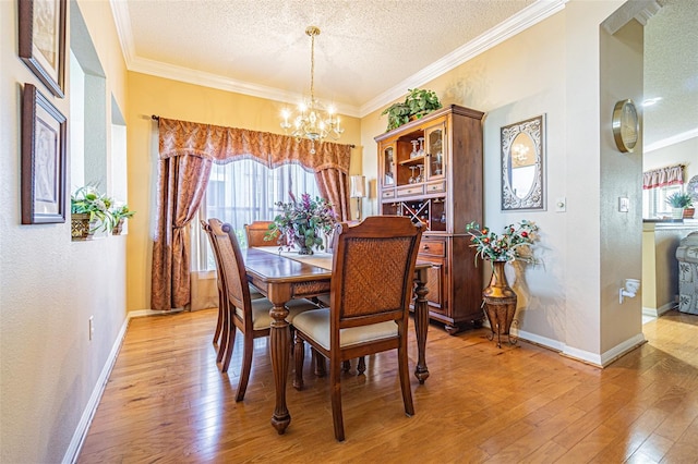 dining room featuring a textured ceiling, a chandelier, ornamental molding, and light wood finished floors