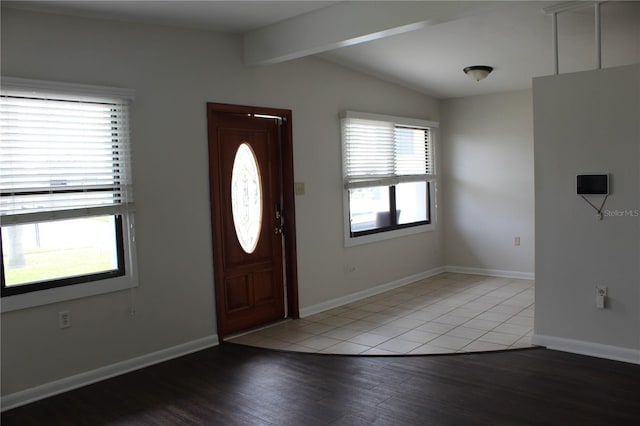 foyer with light wood-style flooring, lofted ceiling with beams, and baseboards