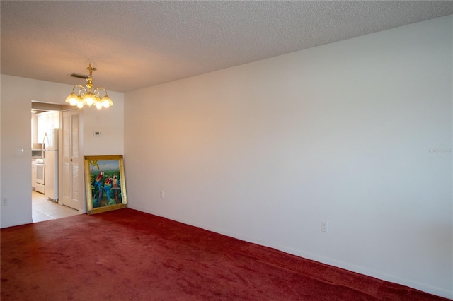 unfurnished room featuring light carpet, a chandelier, a textured ceiling, and visible vents