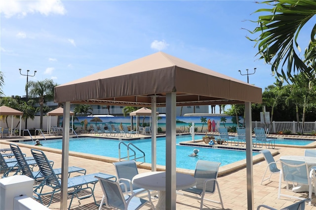 community pool with a gazebo, fence, and a patio