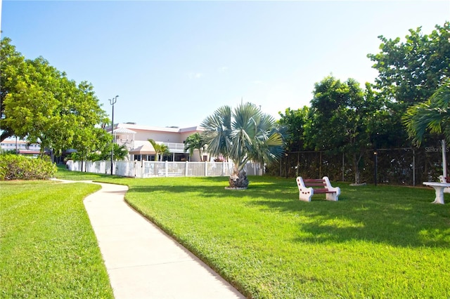 view of property's community with a lawn and fence