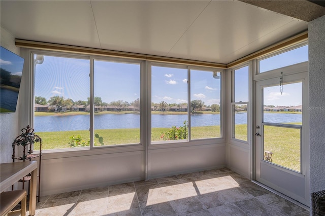 unfurnished sunroom featuring a water view and stone finish flooring