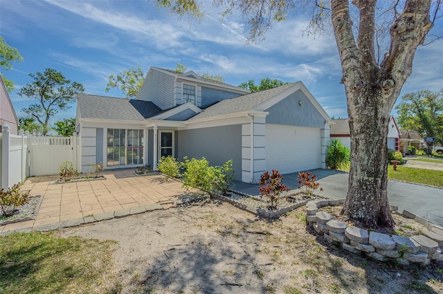 view of front of house featuring stucco siding, driveway, fence, roof with shingles, and an attached garage