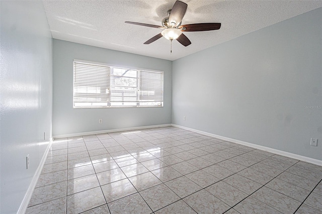 spare room with light tile patterned flooring, a ceiling fan, baseboards, and a textured ceiling