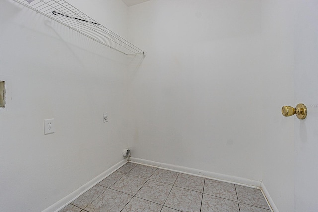 laundry area with electric dryer hookup, baseboards, light tile patterned flooring, and laundry area