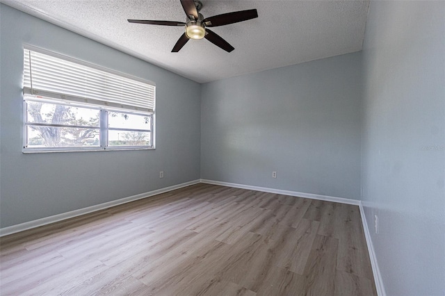 empty room with baseboards, a textured ceiling, ceiling fan, and wood finished floors