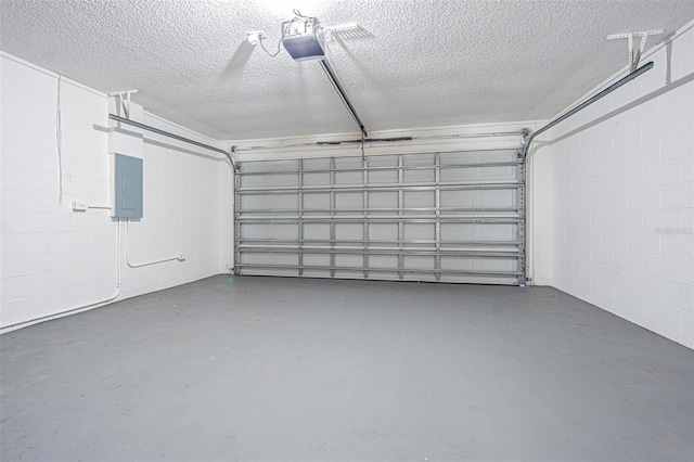 garage featuring concrete block wall, electric panel, and a garage door opener