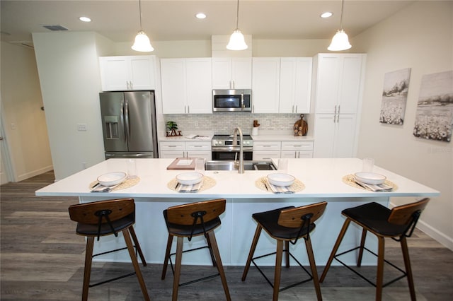 kitchen with tasteful backsplash, visible vents, an island with sink, appliances with stainless steel finishes, and dark wood-style floors