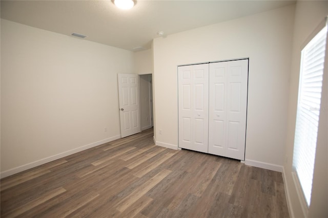 9445 Eldridge Rd, Spring Hill, FL 34608 - unfurnished bedroom with wood finished floors, multiple windows, and a closet