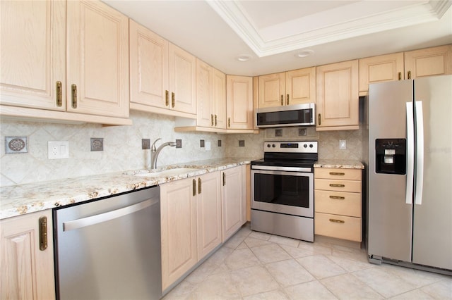 1621 Gulf Blvd Unit 308, Clearwater Beach, FL 33767 - kitchen featuring appliances with stainless steel finishes, light brown cabinets, crown molding, a raised ceiling, and tasteful backsplash