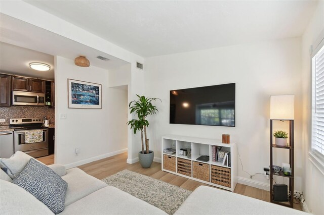 living area with light wood-style flooring, baseboards, and visible vents