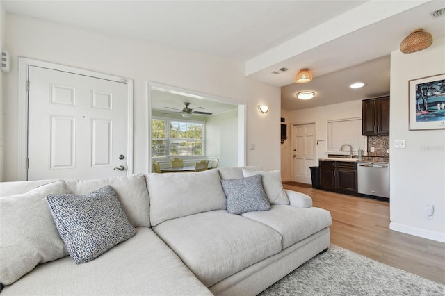 living area featuring light wood-style flooring, baseboards, visible vents, and ceiling fan