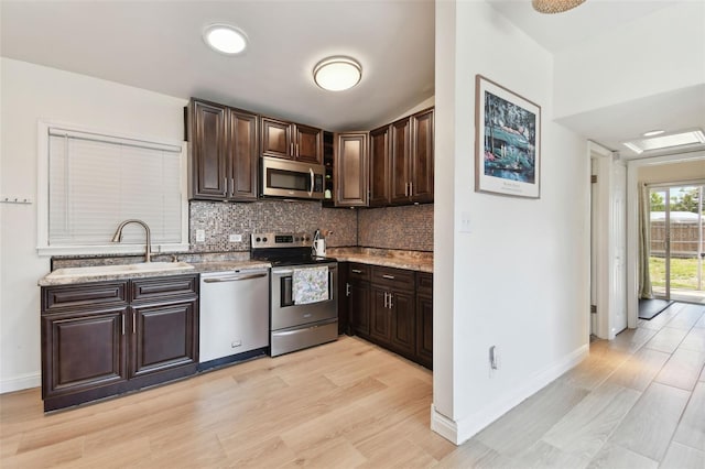 kitchen featuring tasteful backsplash, dark brown cabinets, appliances with stainless steel finishes, and a sink