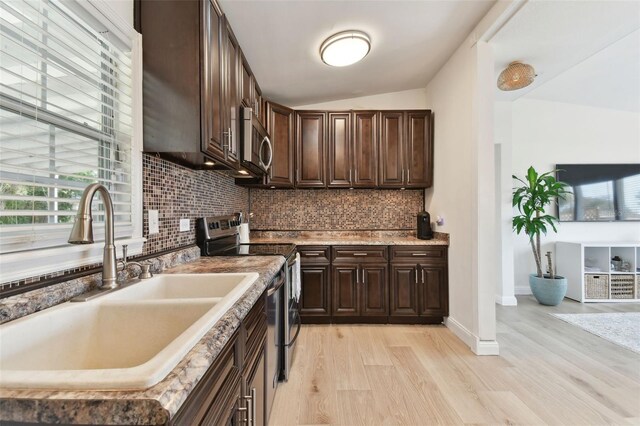 kitchen with a sink, backsplash, stainless steel appliances, light wood-style floors, and dark brown cabinetry