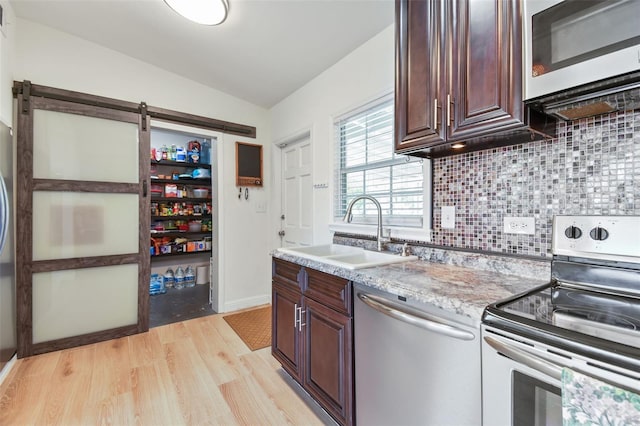 kitchen with a sink, dark brown cabinets, light wood finished floors, and stainless steel appliances