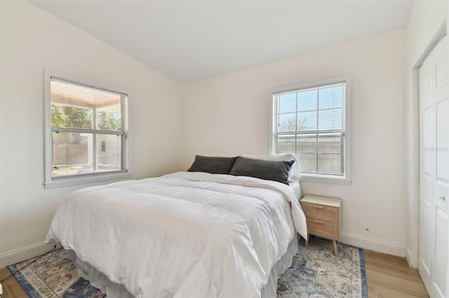 bedroom featuring vaulted ceiling, baseboards, and light wood finished floors