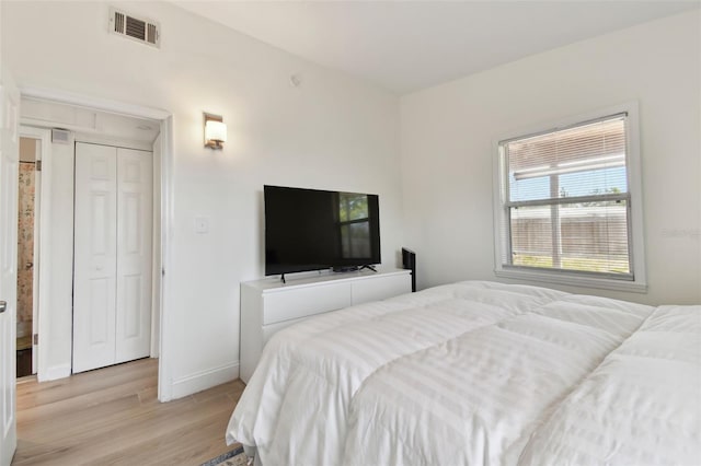 bedroom featuring visible vents, light wood-style flooring, and baseboards