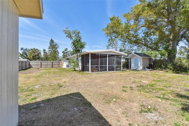 view of yard featuring a fenced backyard, a storage shed, an outdoor structure, and a sunroom