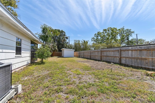 view of yard with cooling unit, an outdoor structure, a fenced backyard, and a storage shed