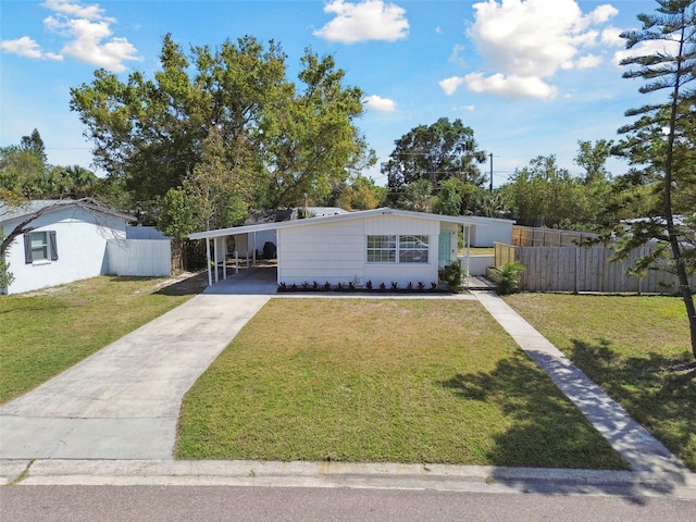 view of front of home with an attached carport, concrete driveway, fence, and a front yard