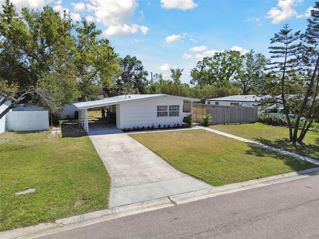mid-century modern home featuring an attached carport, fence, a front yard, and driveway