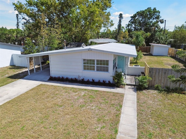 view of front facade featuring a carport, concrete driveway, a front lawn, and fence