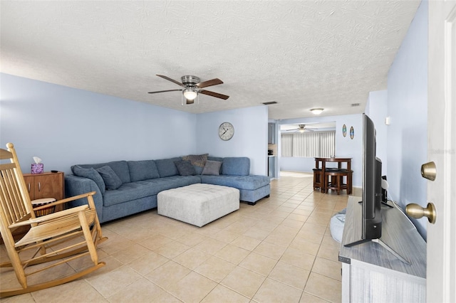 living area with light tile patterned floors, a ceiling fan, visible vents, and a textured ceiling