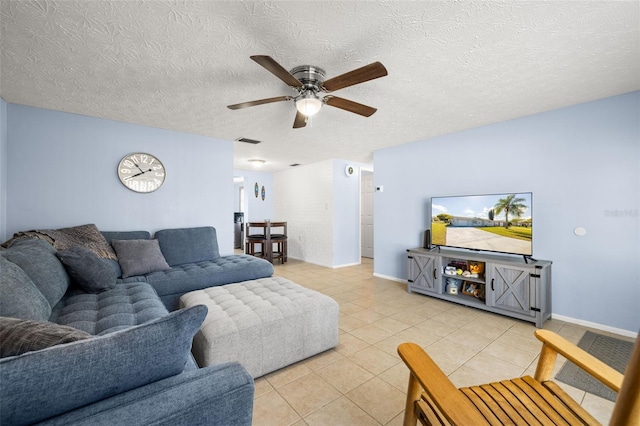 living room featuring visible vents, a ceiling fan, a textured ceiling, light tile patterned floors, and baseboards