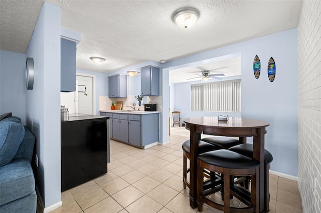 kitchen with ceiling fan, light tile patterned floors, gray cabinets, a textured ceiling, and a sink