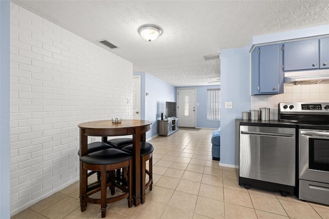 kitchen featuring visible vents, backsplash, under cabinet range hood, stainless steel appliances, and blue cabinets