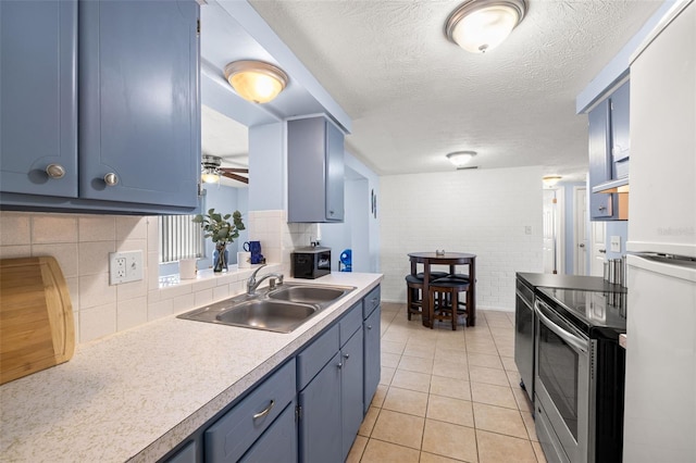 kitchen featuring blue cabinets, a sink, and stainless steel range with electric cooktop