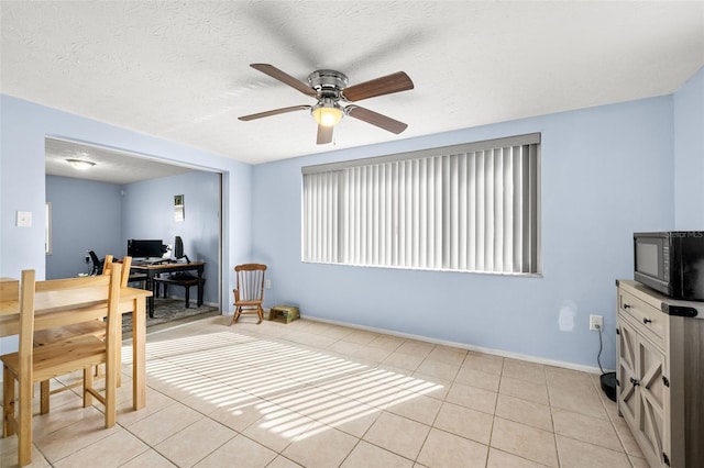 office area with light tile patterned flooring, a textured ceiling, baseboards, and ceiling fan