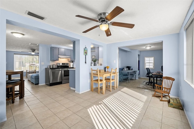 living room with visible vents, a ceiling fan, a textured ceiling, light tile patterned floors, and baseboards