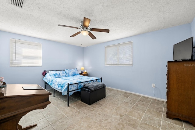 bedroom featuring baseboards, a ceiling fan, visible vents, and a textured ceiling