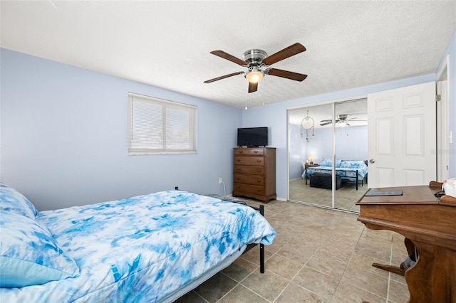 bedroom featuring a closet, tile patterned flooring, a textured ceiling, and a ceiling fan